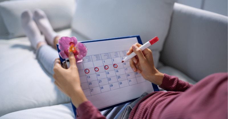 Mulher segurando calendário para controlar ciclo menstrual e acompanhar exames hormonais para engravidar
