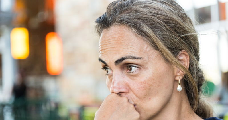 Mulher de meia idade pensativa, representando mudanças corporais e gordura abdominal na menopausa